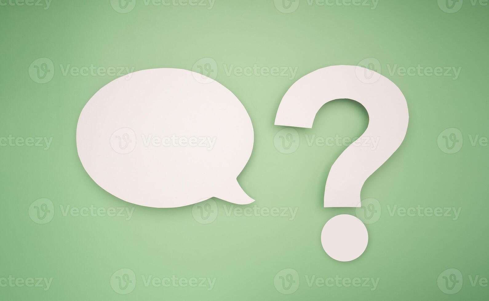 White speech bubble and a white question mark over a green background photo