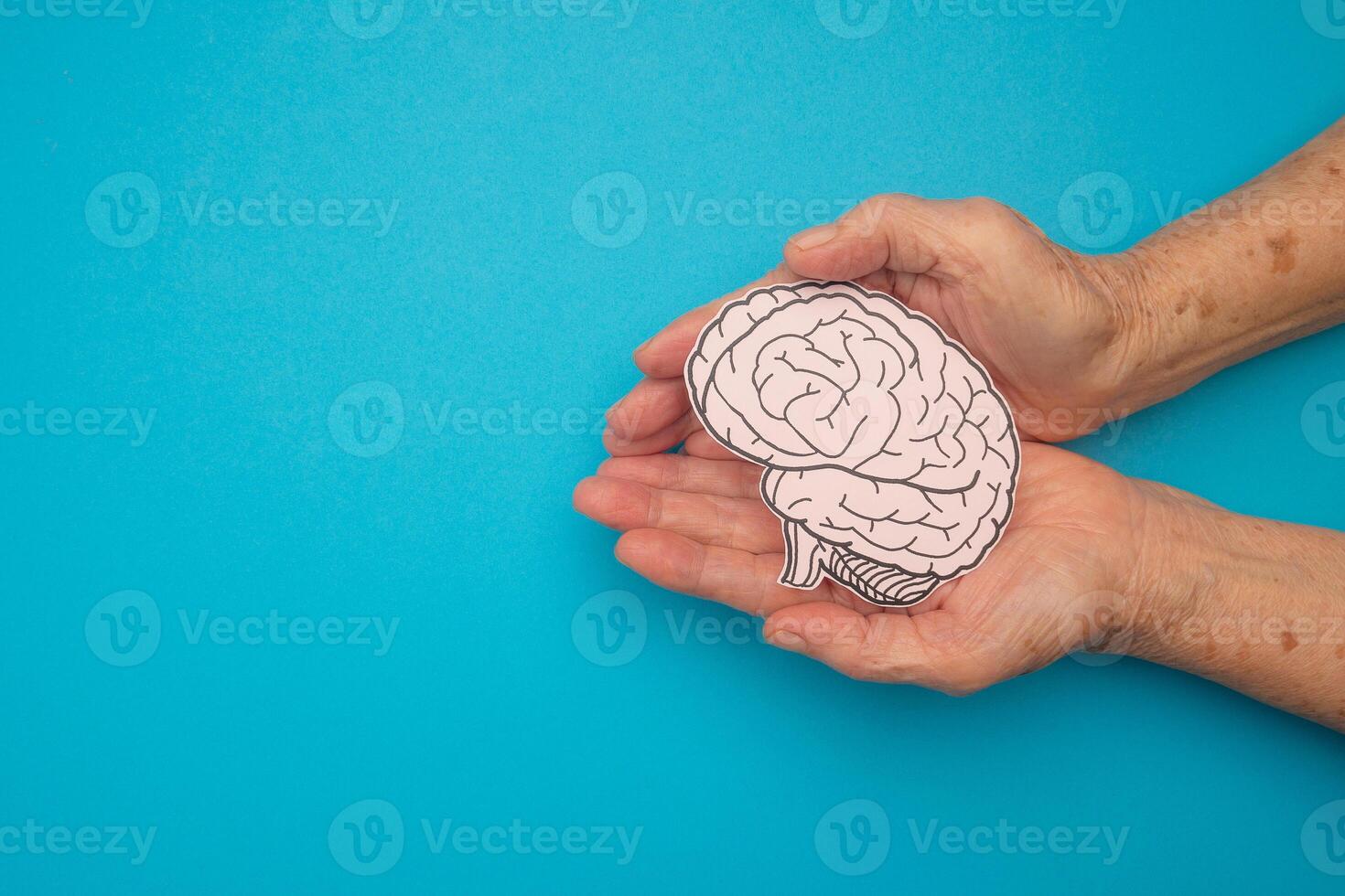 Brain shape made from paper on a palm senior woman on a blue background photo
