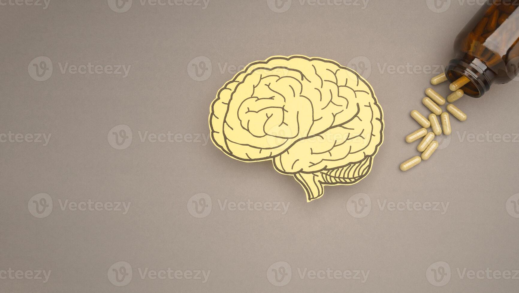 Brain shape made from paper and pills capsules with a bottle on a gray background photo