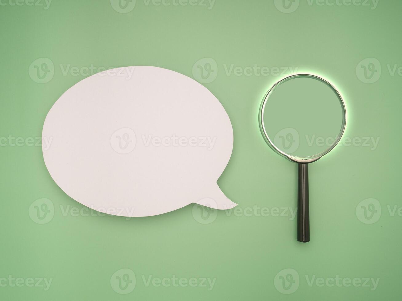 Top view of a blank speech bubble and a magnifying glass on a green background photo