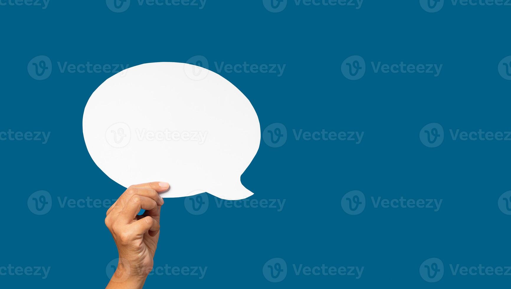 Hand holding of an empty white speech bubble over blue background photo