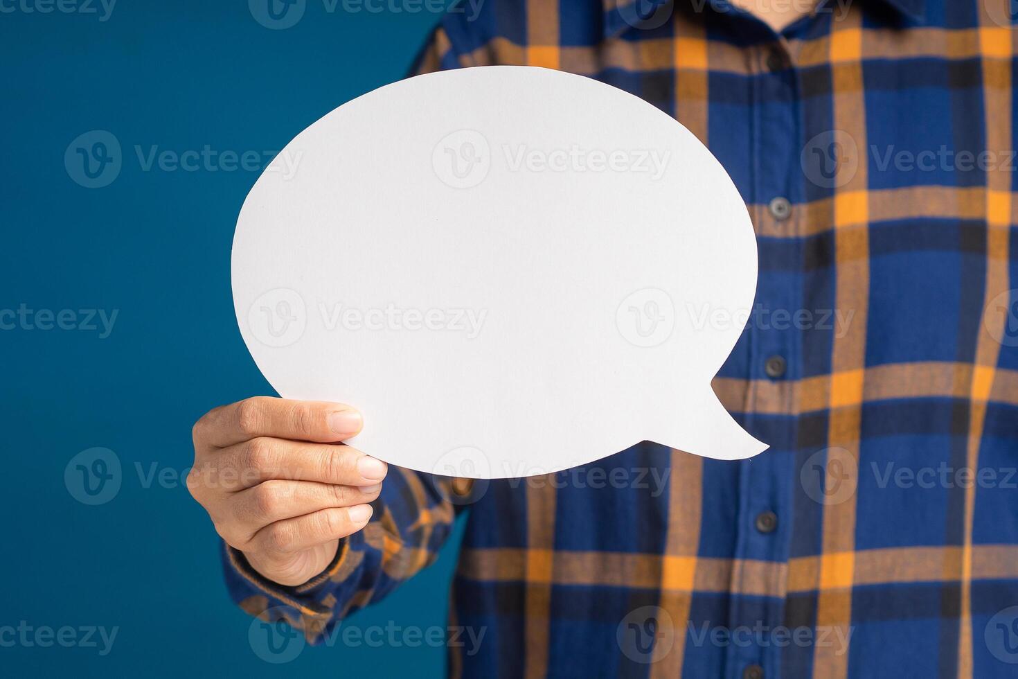 Hand holding of an empty white speech bubble against a blue background photo
