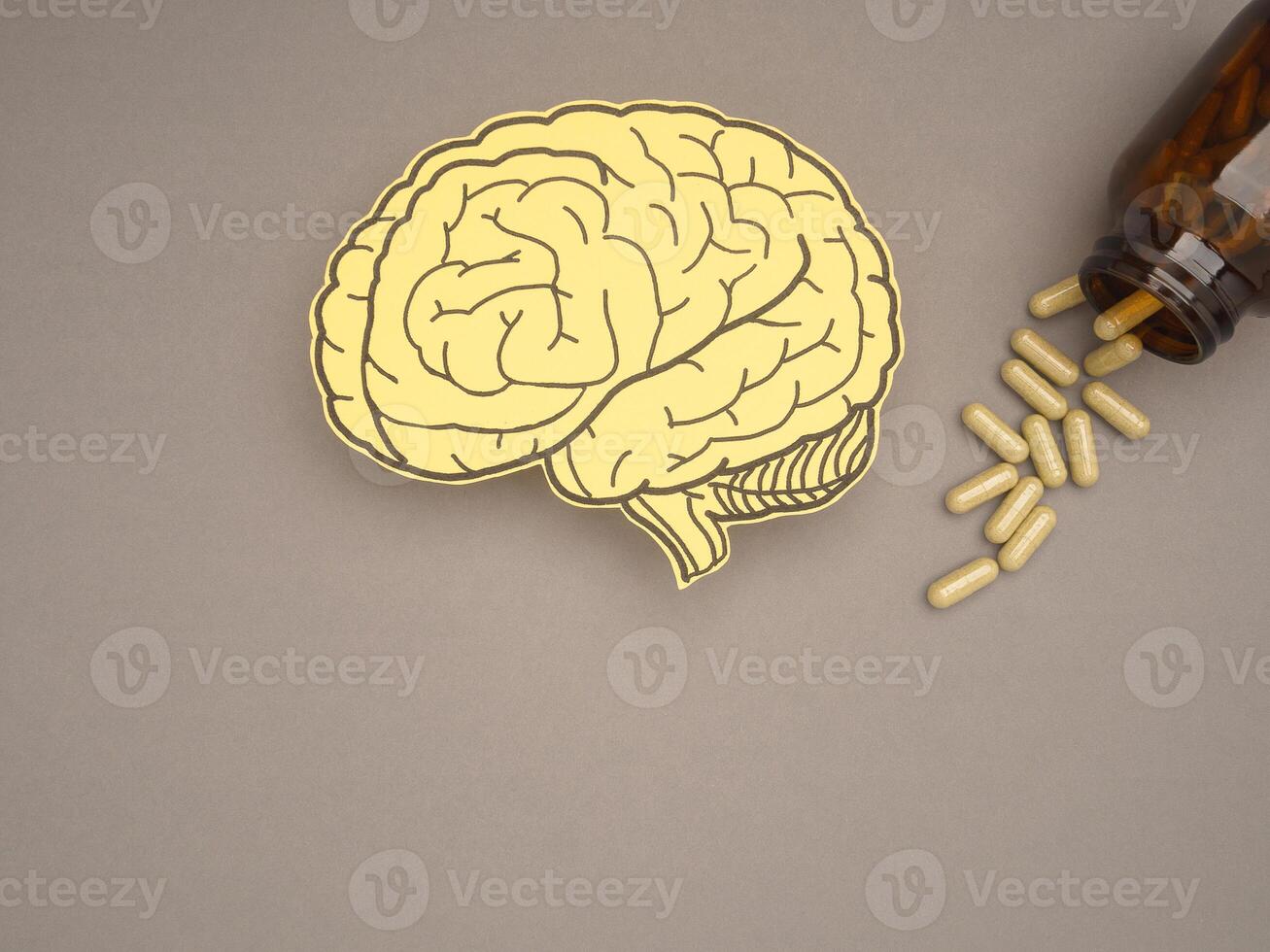 Brain shape made from paper and pills capsules with a bottle on a gray background photo