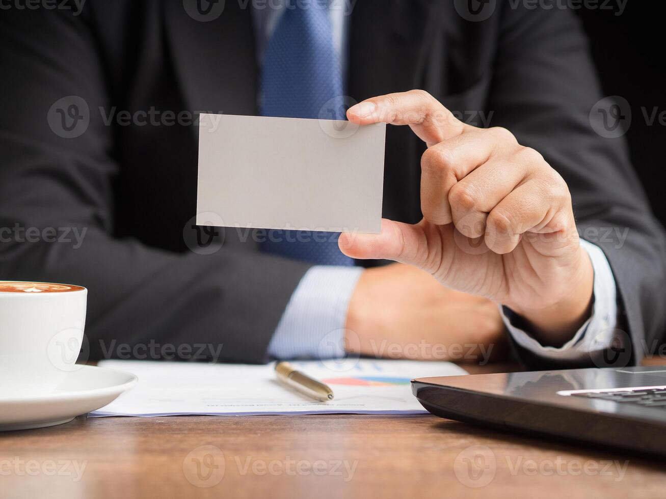 Businessman in a suit holding a name card mockup while sitting in the office photo