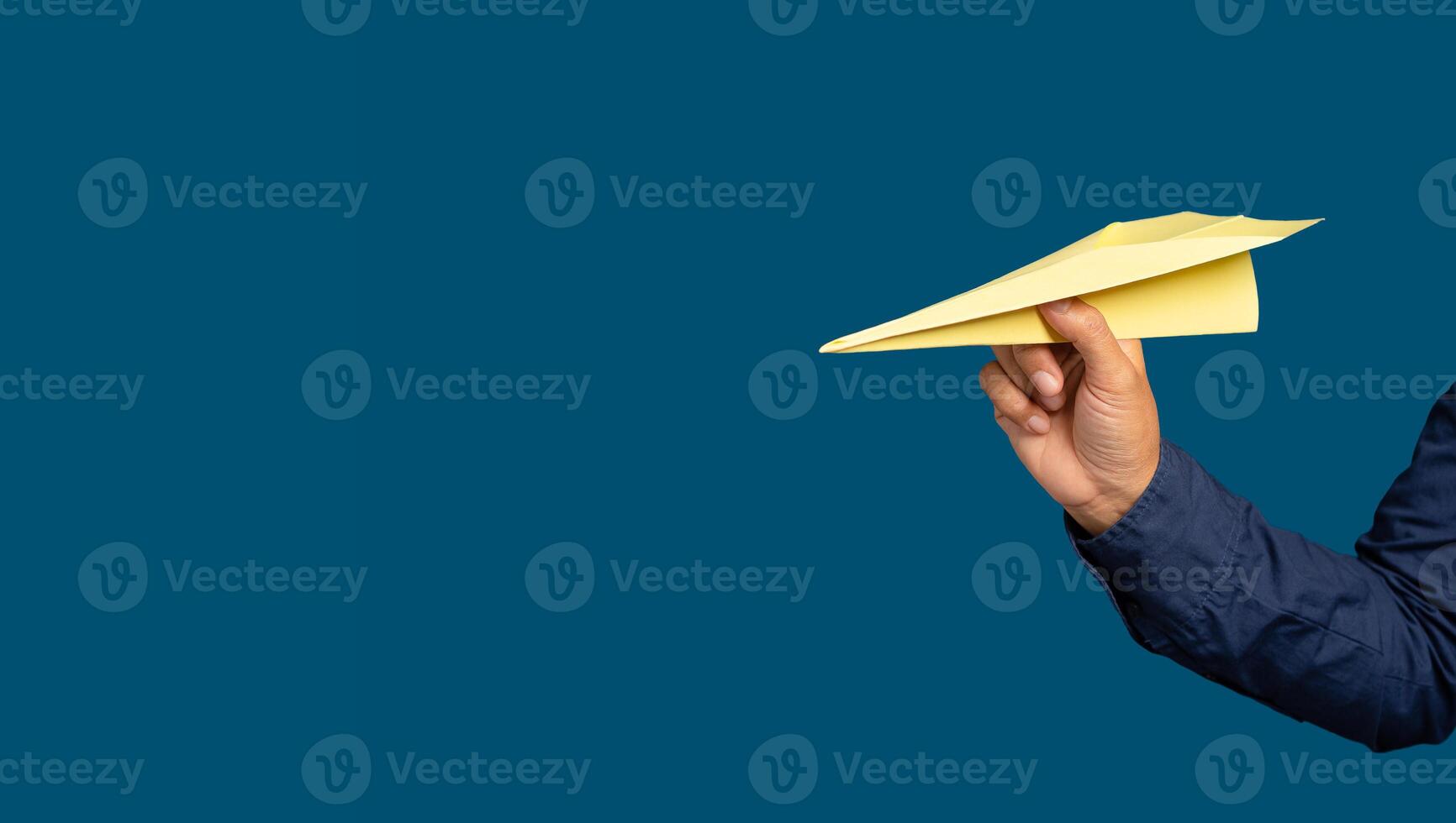 Hand holding a yellow rocket paper on a blue background. Business startup concept photo