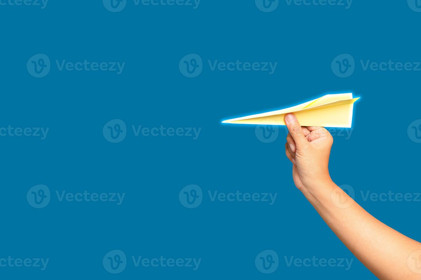 Business startup concept. Hand holding a yellow rocket paper on a blue background. photo