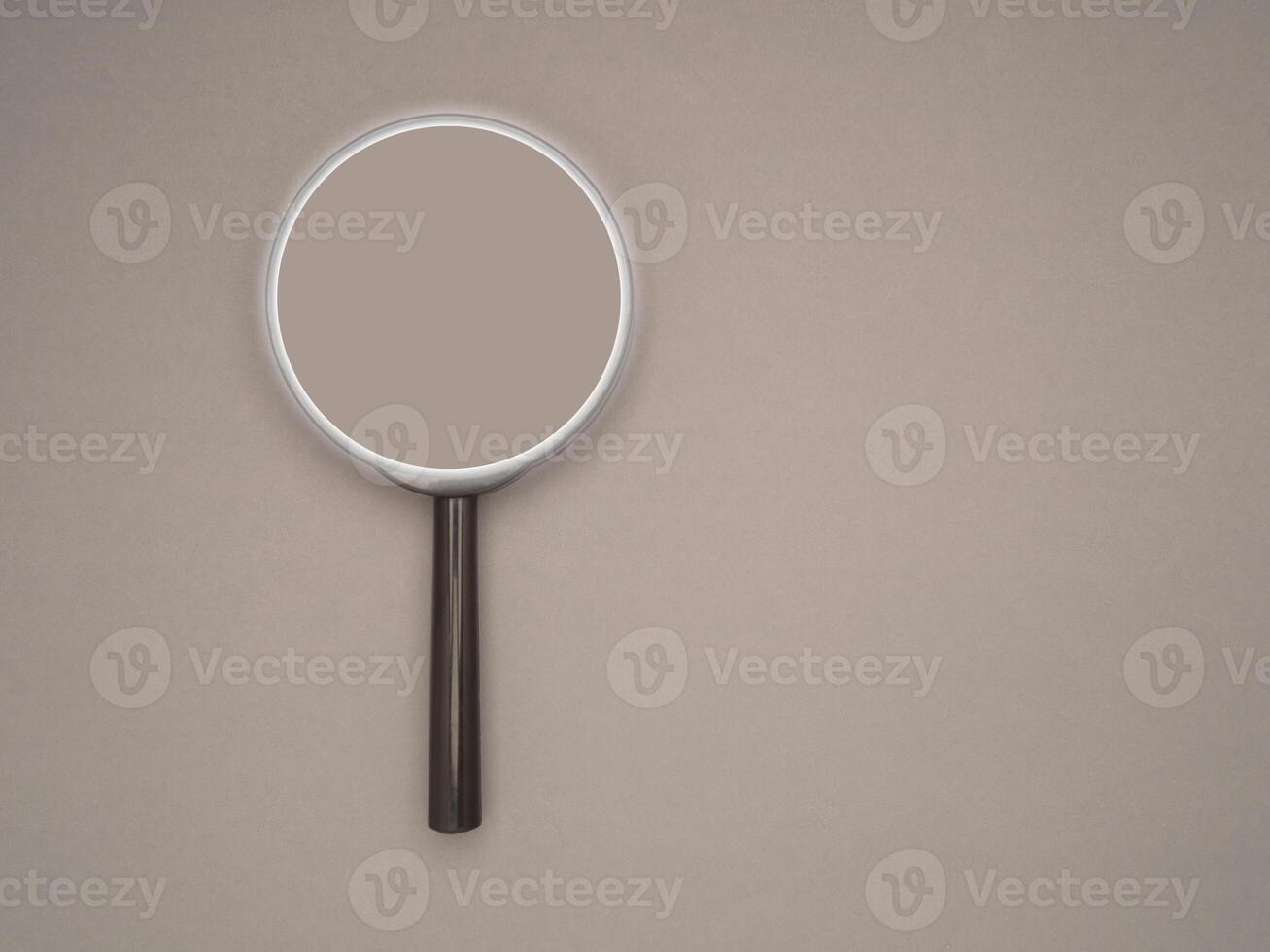 Top view of a magnifying glass on a gray background with space for text photo