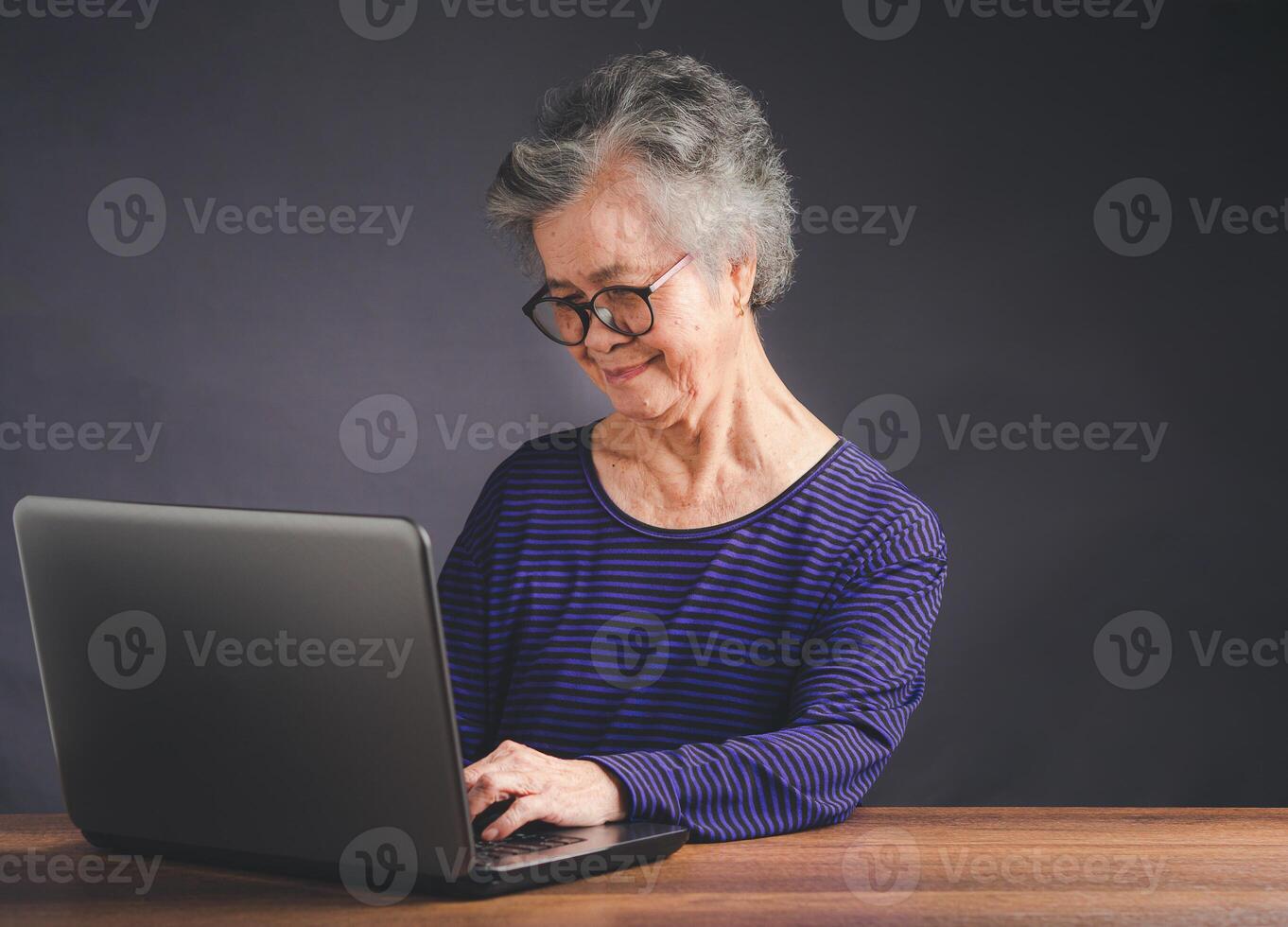 An elderly Asian woman using a laptop for searching data on the internet photo