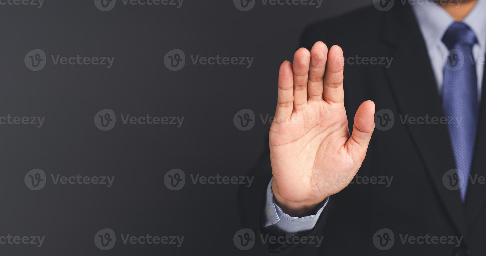 Businessman making stop gesture with his hands while standing on gray background. photo