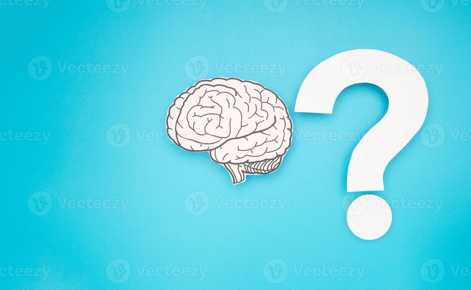 Brain shape made from paper and a white question mark against a blue background photo