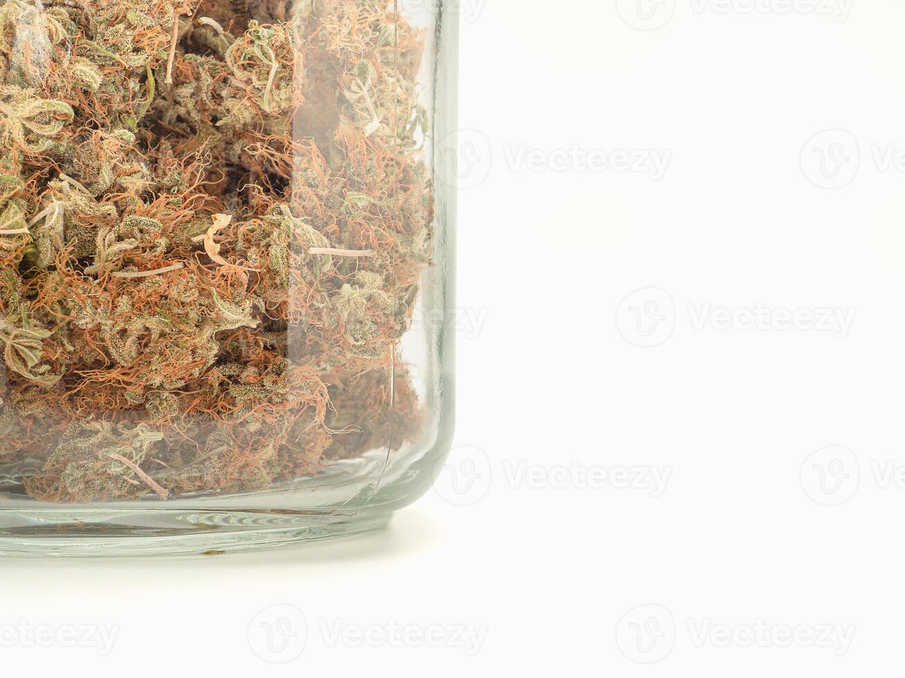 Dry cannabis buds flower in a jar glass on the table isolated on a white background photo
