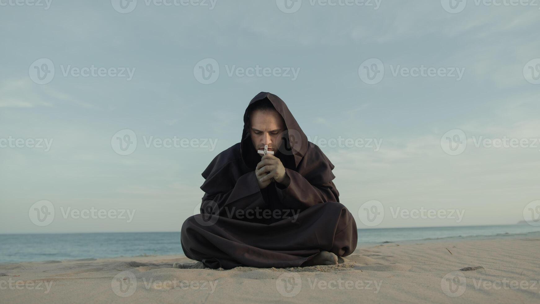 Monk Collected In Prayer Sitting On The Beach In The Evening photo
