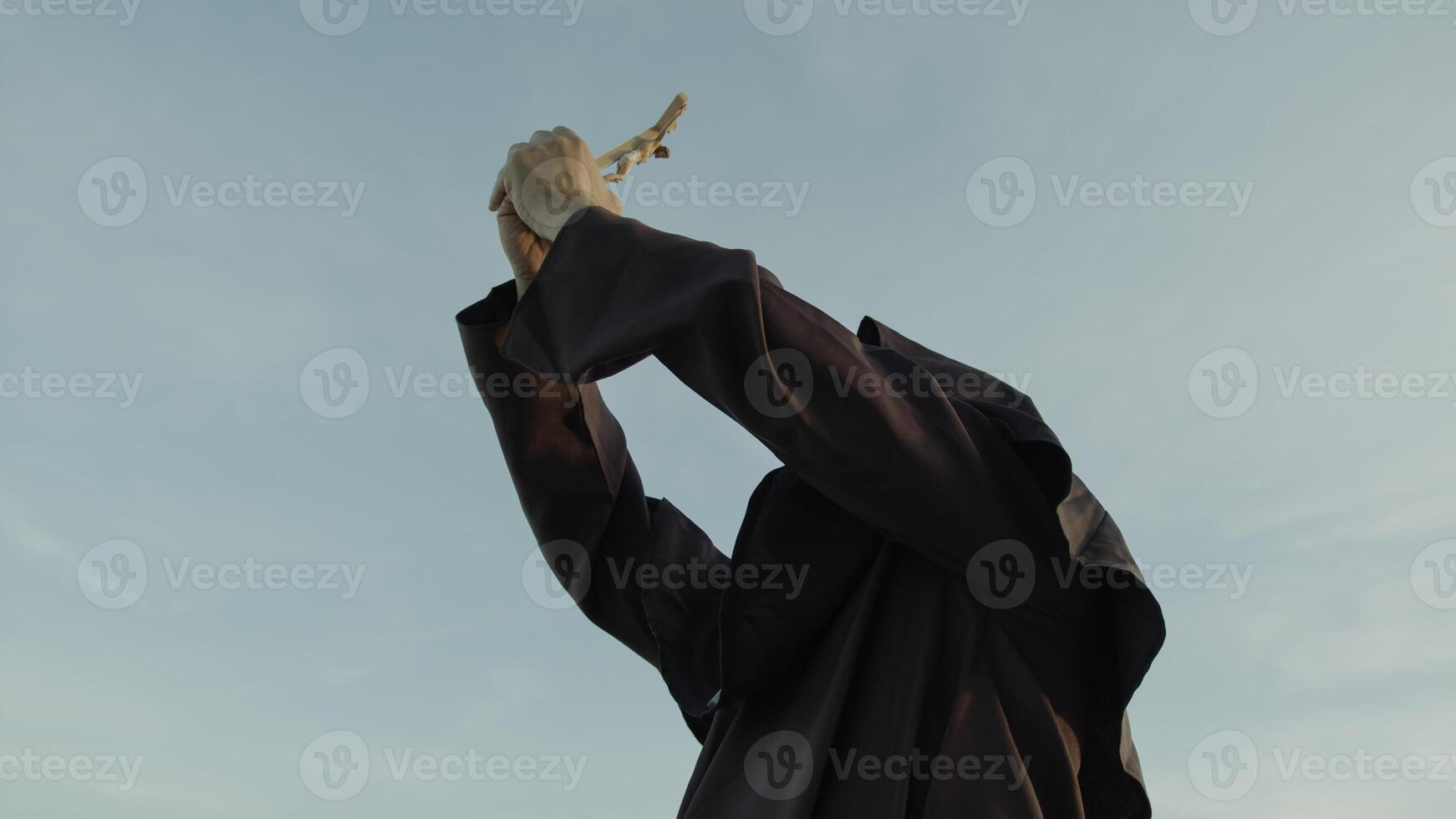 Monk Prays With A Crucifix Of Jesus In His Hand Towards The Celestial Sky photo