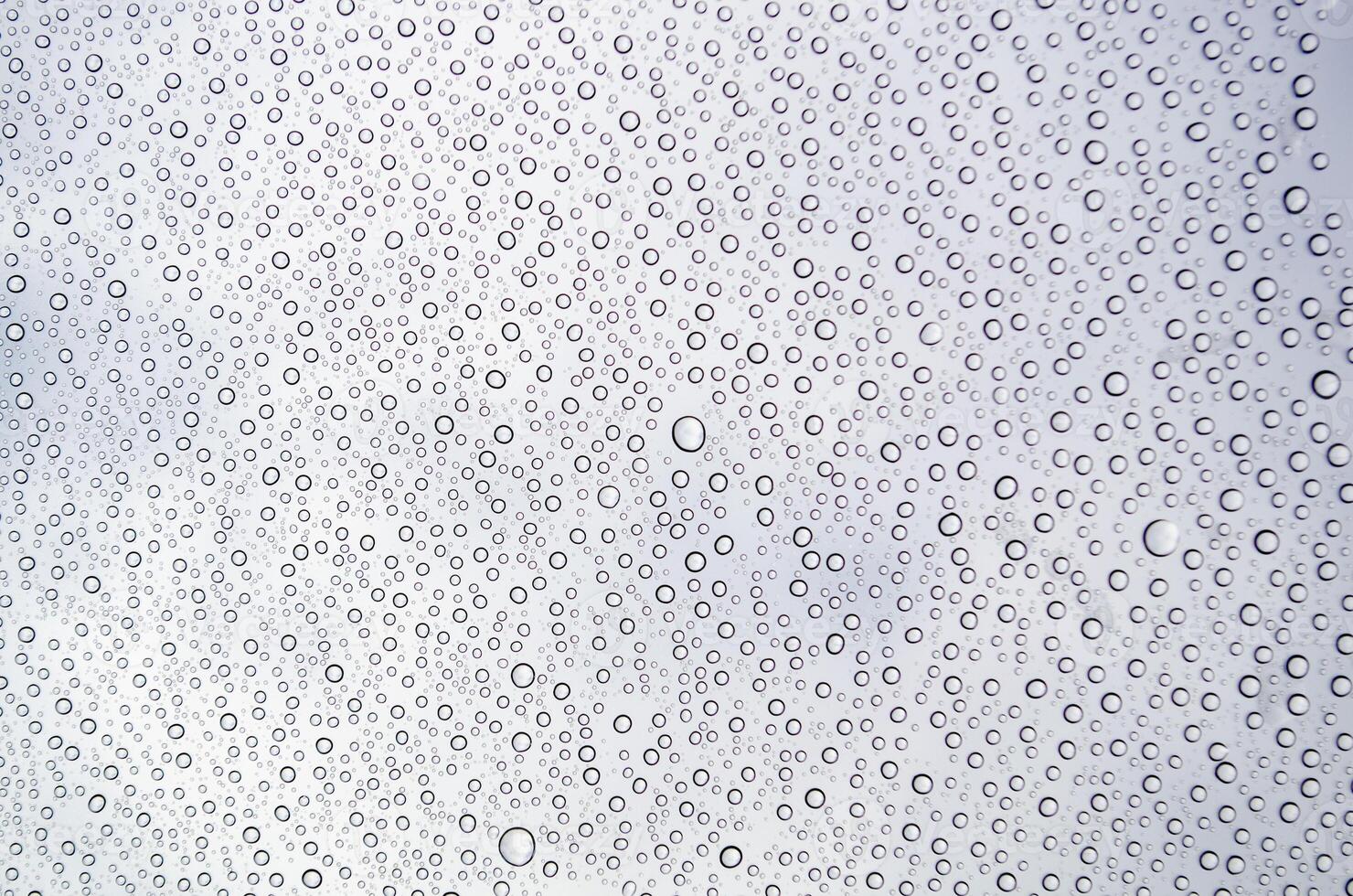 Close-up of droplets clustering on a glass surface after rain. Water texture concept photo