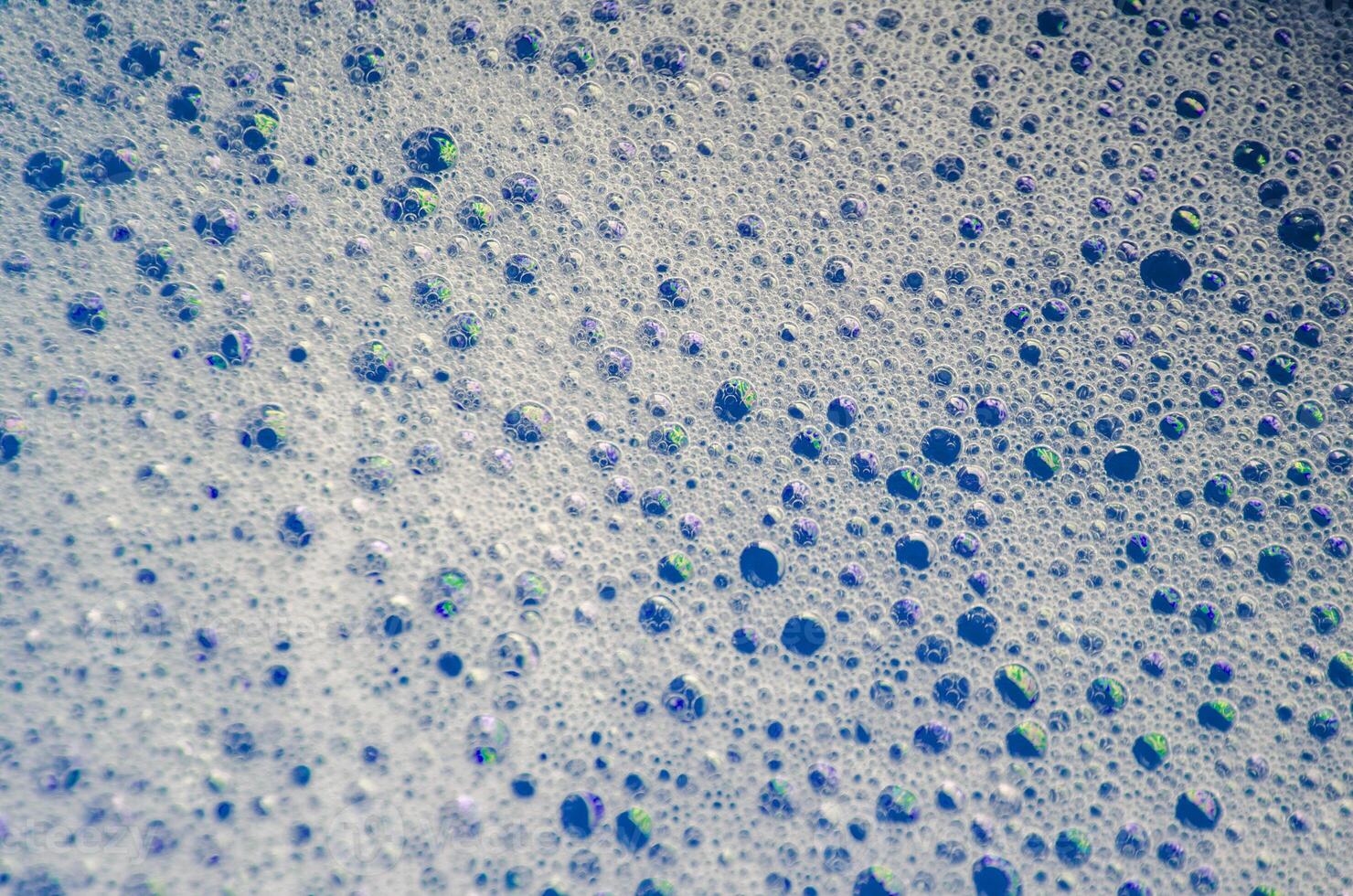 Macro view of bubbles forming on the water surface with blue background photo