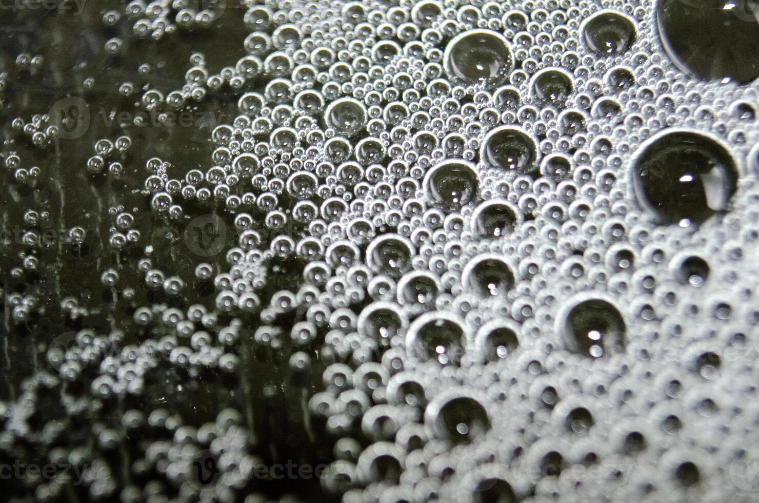 Macro view of bubbles forming on the water surface with dark background photo