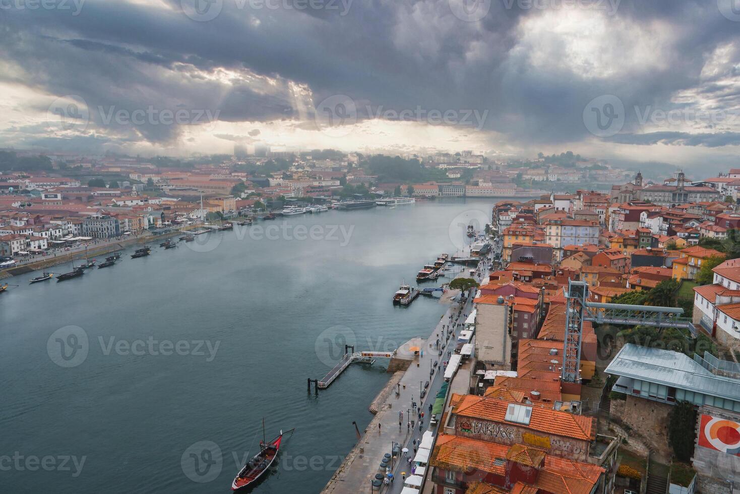 Stunning aerial view of Porto, Portugal, featuring the Douro River, Ribeira district, and Dom Luis I Bridge under a dramatic sky with sunlight rays. photo