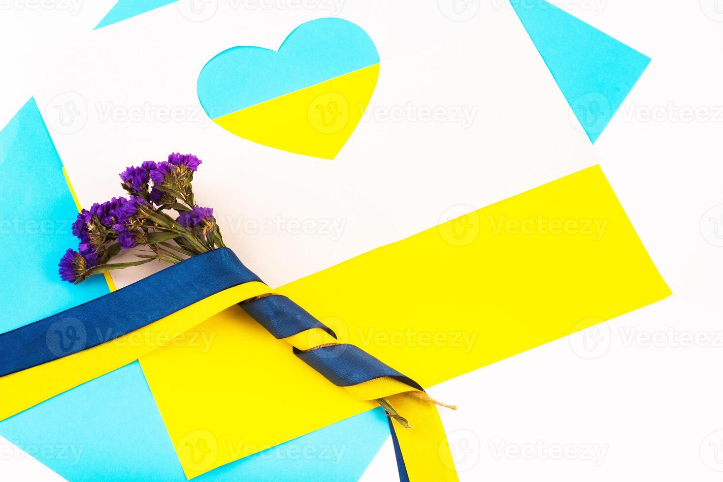 heart cut out of paper and painted in blue and yellow colors and flowers in ribbon of flag photo