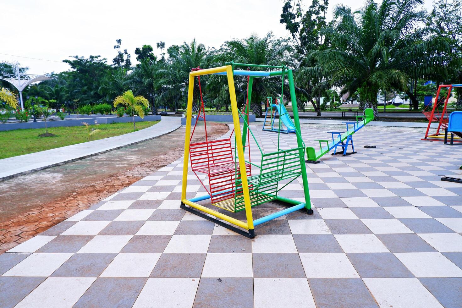 hanging swing chair that is usually found in parks or playgrounds. hanging swing chair made of iron with a combination of yellow, green, and red colors. photo
