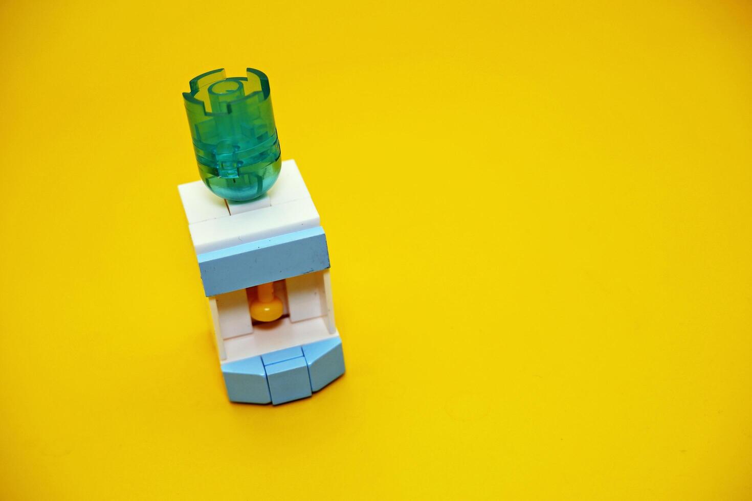 mini dispenser toy assembled from plastic blocks. dispenser toy isolated on yellow background. photo