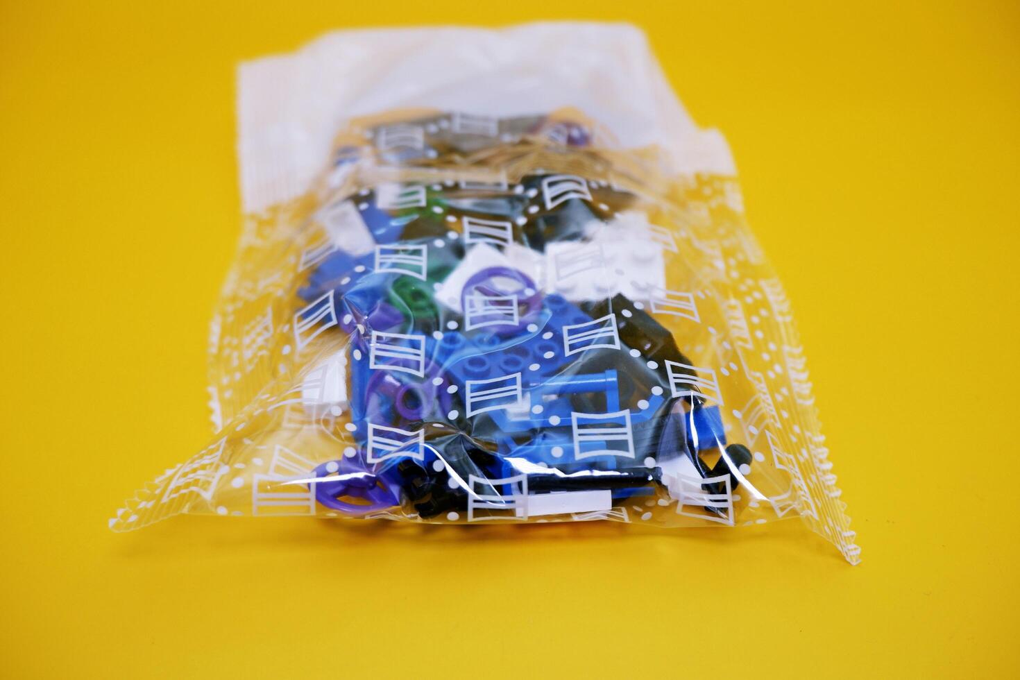 a collection of toy blocks still in plastic. a collection of toy blocks isolated on a yellow background. toys that are played by stacking them like stacking bricks. photo