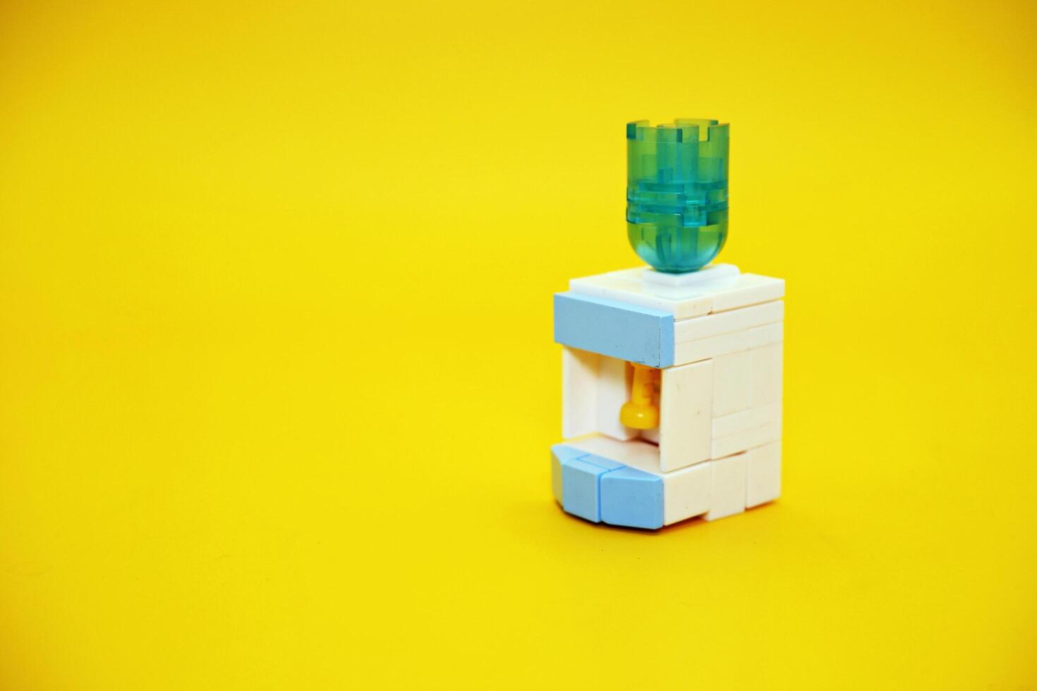 mini dispenser toy assembled from plastic blocks. dispenser toy isolated on yellow background. photo