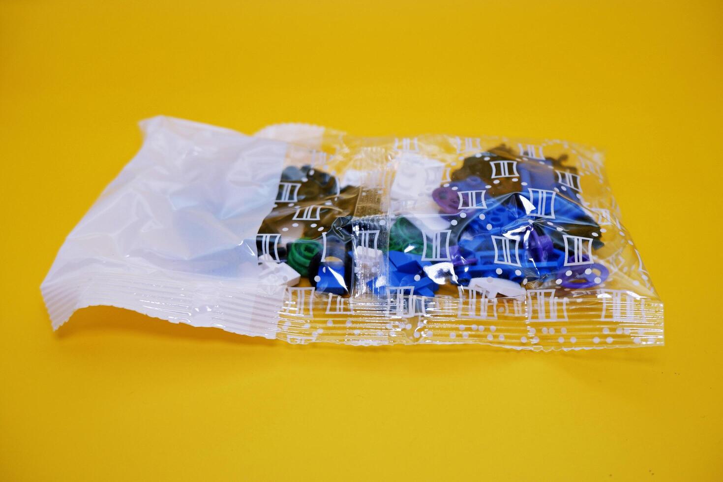 a collection of toy blocks still in plastic. a collection of toy blocks isolated on a yellow background. toys that are played by stacking them like stacking bricks. photo