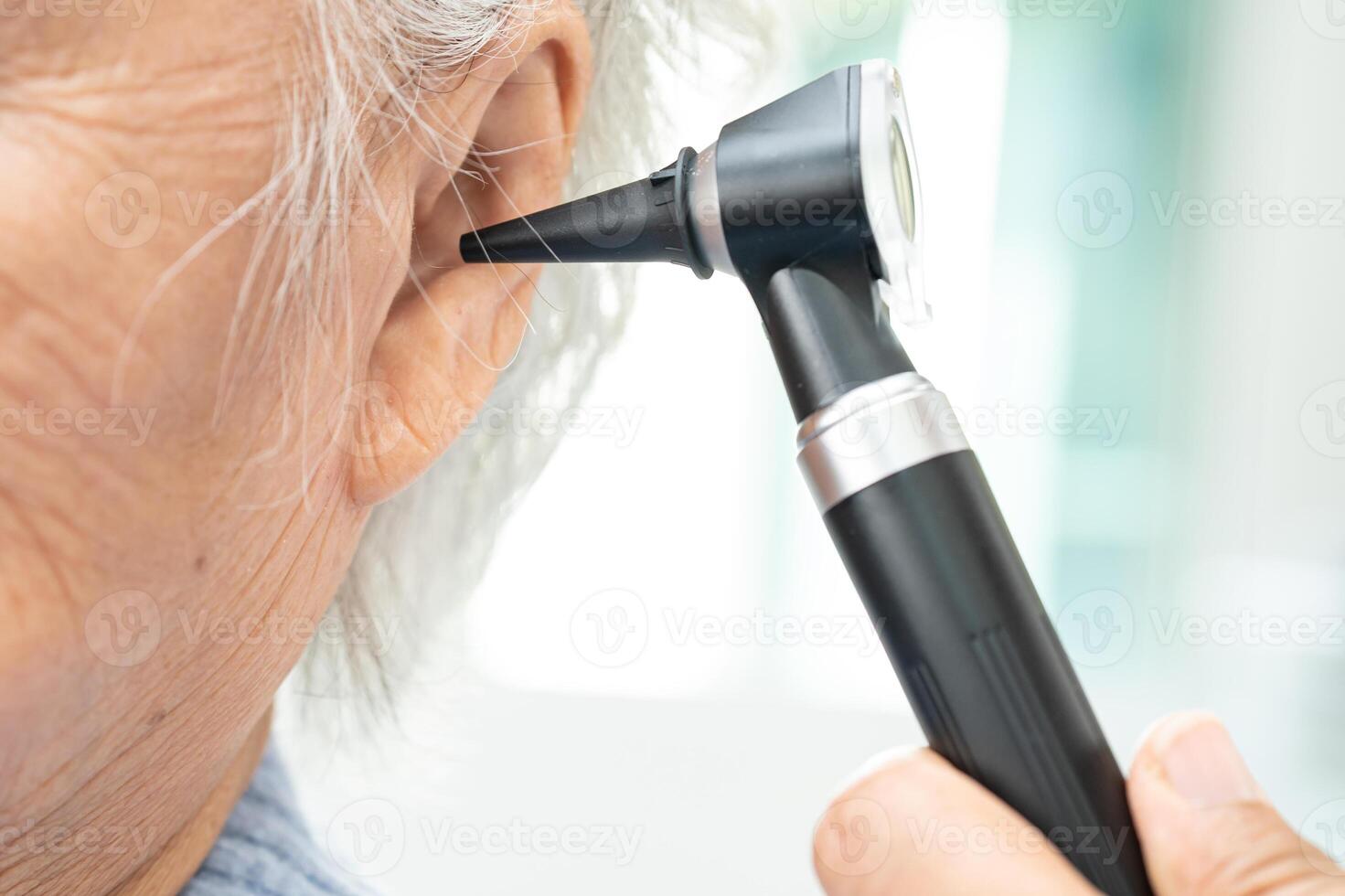 Audiologist or ENT doctor use otoscope checking ear of asian senior woman patient treating hearing loss problem. photo