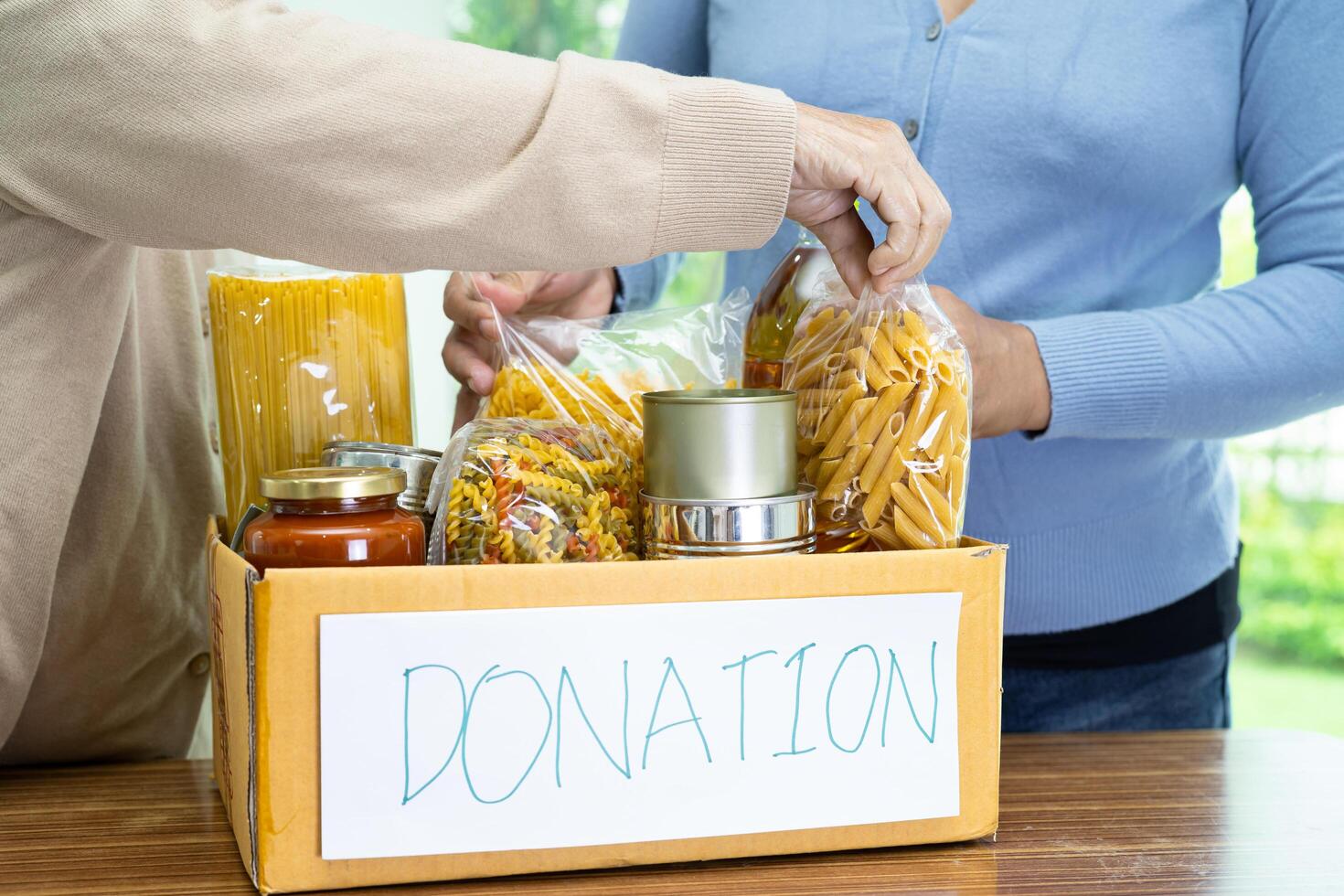 Volunteers putting various dry food in donation box for help people. photo