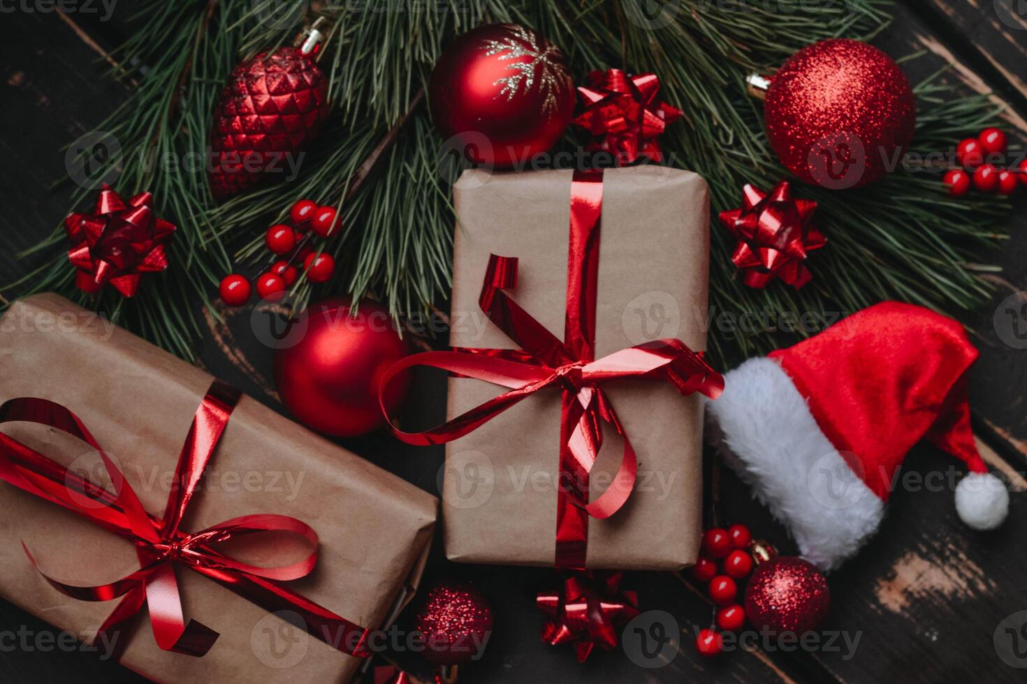 Top view photo Christmass flatlay gift boxes,red christmas tree toys,Santa hat and spruce brance on wooden background. Xmas backdrop with space for text.Copyspace.Close up.
