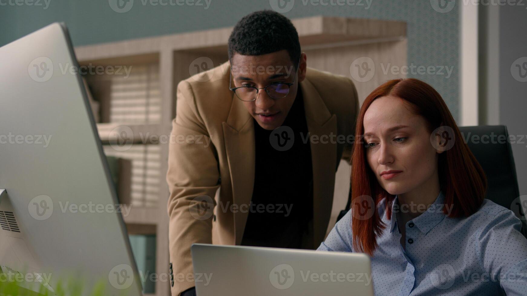 African American man leader mentor helping woman employee teaching intern explaining online job on computer laptop business coaching diverse smiling colleagues businessman businesswoman work in office photo