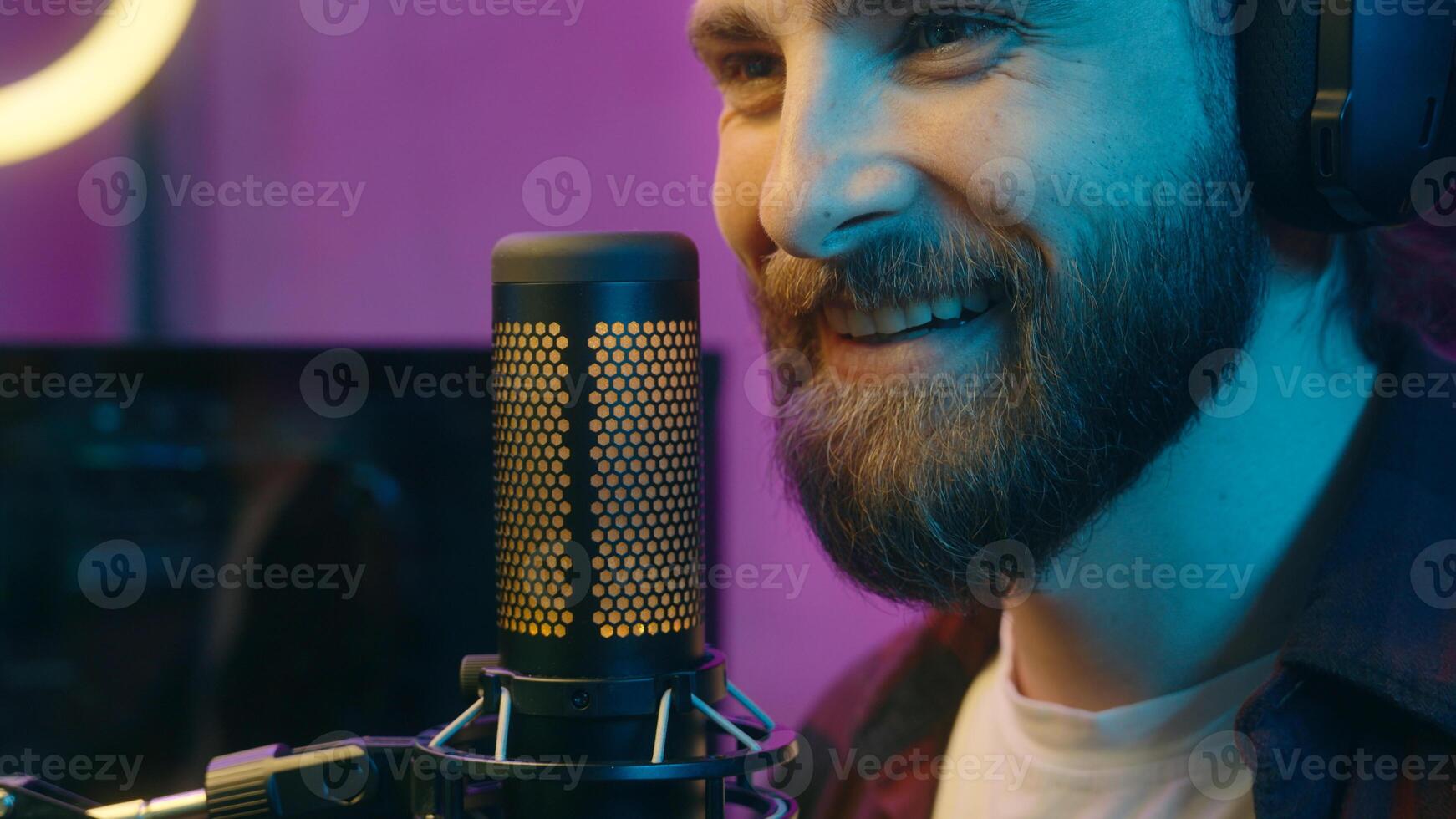 Happy Caucasian man carefree gamer male guy influencer in headphones cyber sport radio blogger talking in microphone stream online on Internet broadcast content home neon popular streamer speak smile photo
