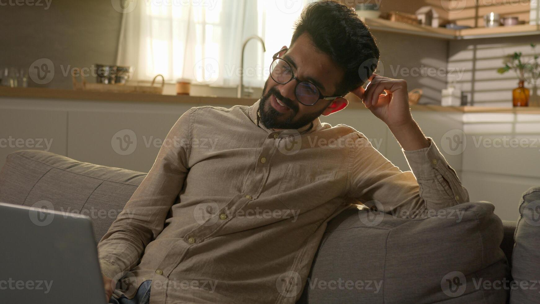 Shocked upset Indian Arabian man guy business work from home kitchen negative bad result worried anxious male freelancer on couch sofa read laptop notification computer problem fail difficult crisis photo