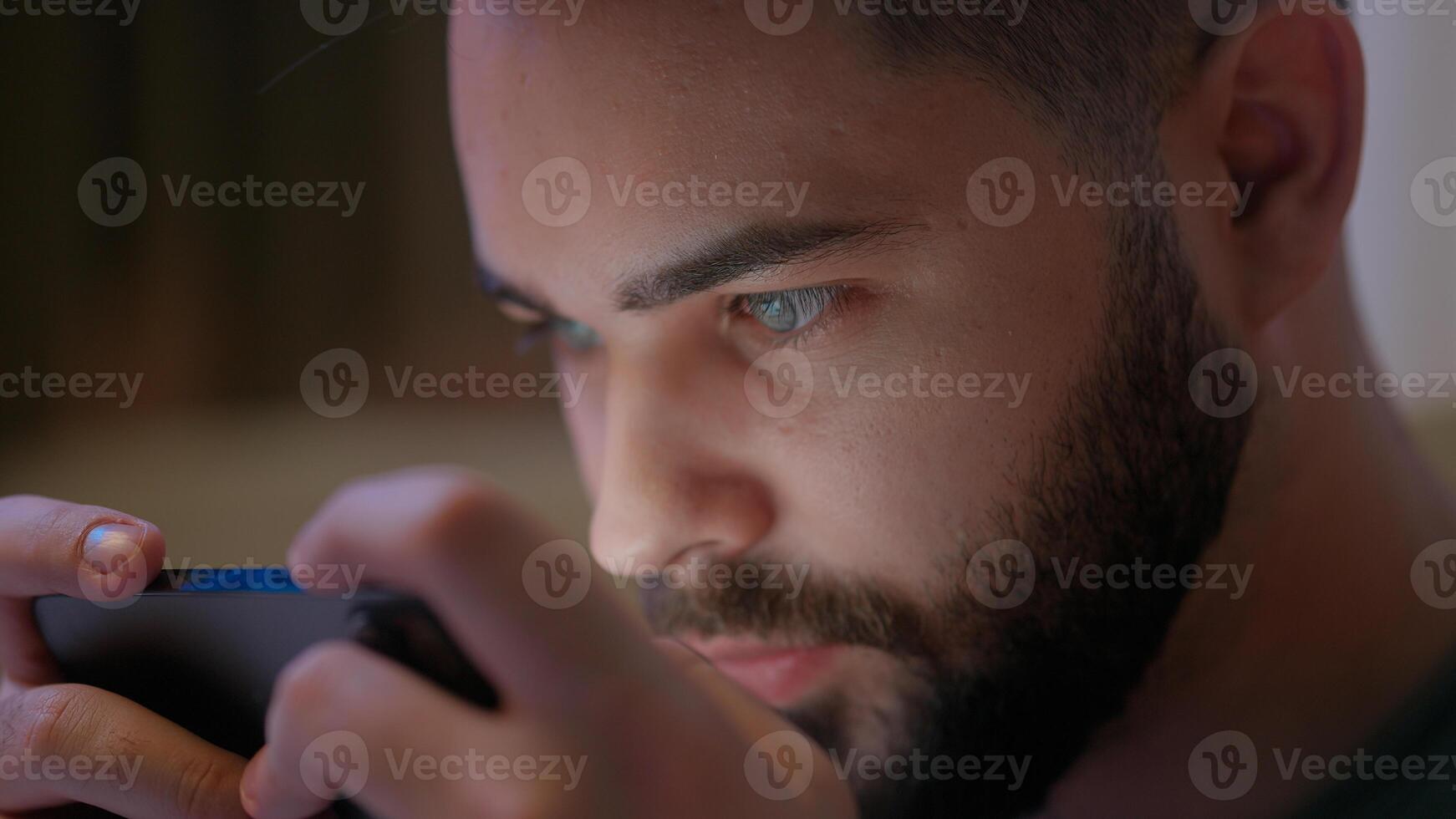 Close up Caucasian man using mobile phone smartphone cellphone gadget online play internet game stuck addict deterioration vision eyes health guy male bed bedroom network looking connection cyberspace photo