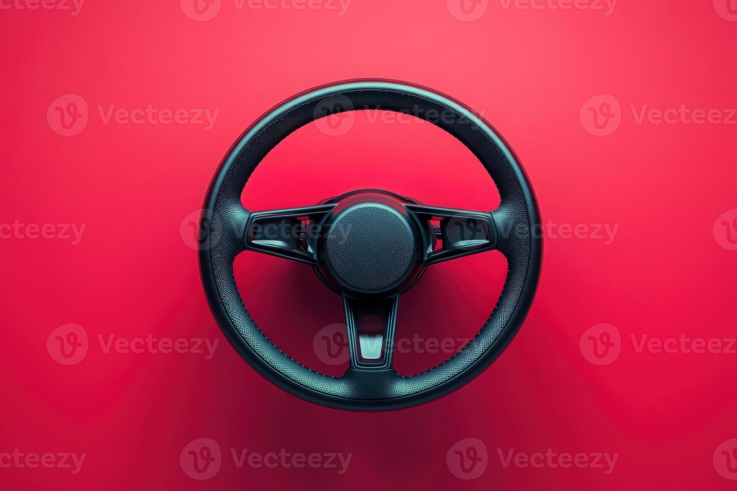 The focus is on a sleek and modern steering wheel, showcasing its minimalist design against a striking red backdrop, highlighting form and function. photo