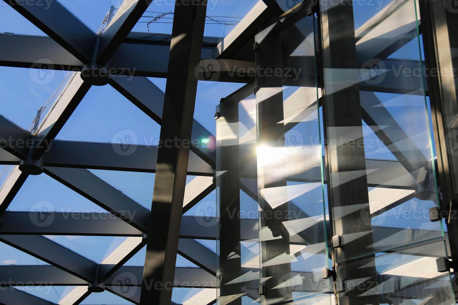 Modern Architectural Design showcasing intricate Geometric Patterns and Glass divisions, accentuated Sunlight reflection. Combination metal racks and glass Partitions reflects through blue sky photo