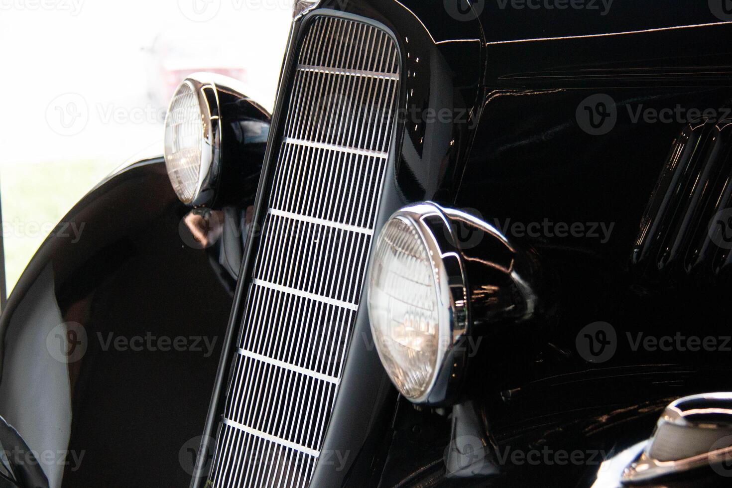 Closeup of Vintage Classic Car featuring a prominent front Grille and shiny Black Finish. Sleek Design highlight the Elegance and Craftsmanship of Antique Automobiles, Historical vehicle enthusiasts photo
