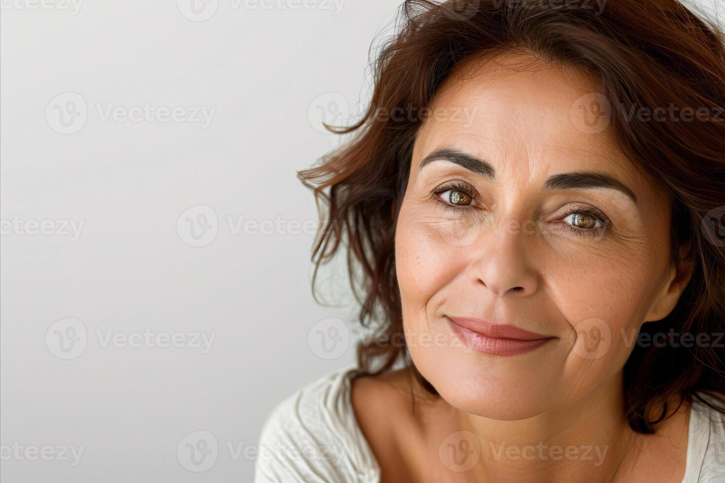 Cropped hispanic beautiful calm smiling middle aged woman looking at camera on white background photo