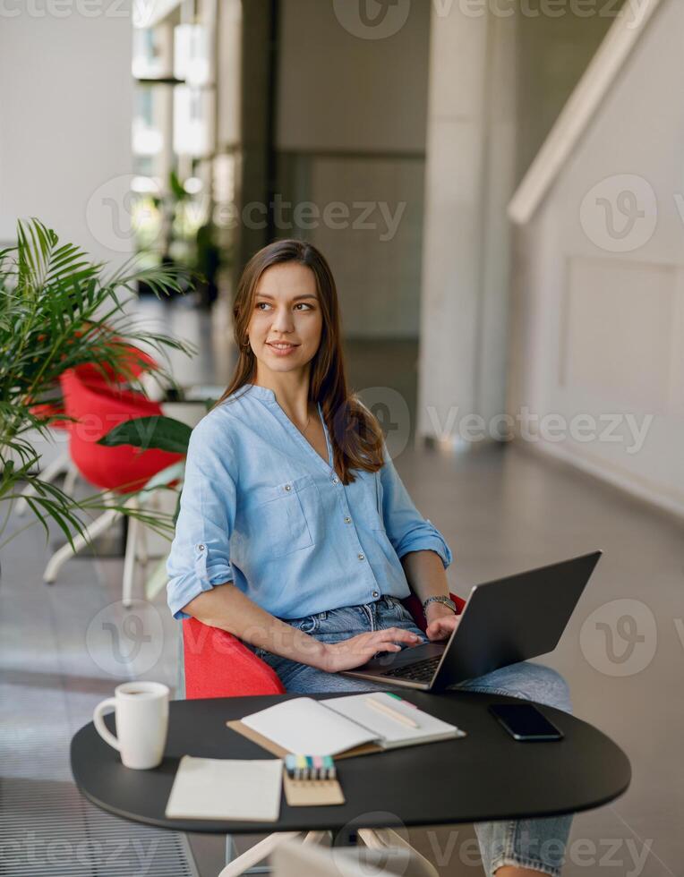 A young professional woman is working on a laptop in a sleek modern office space photo