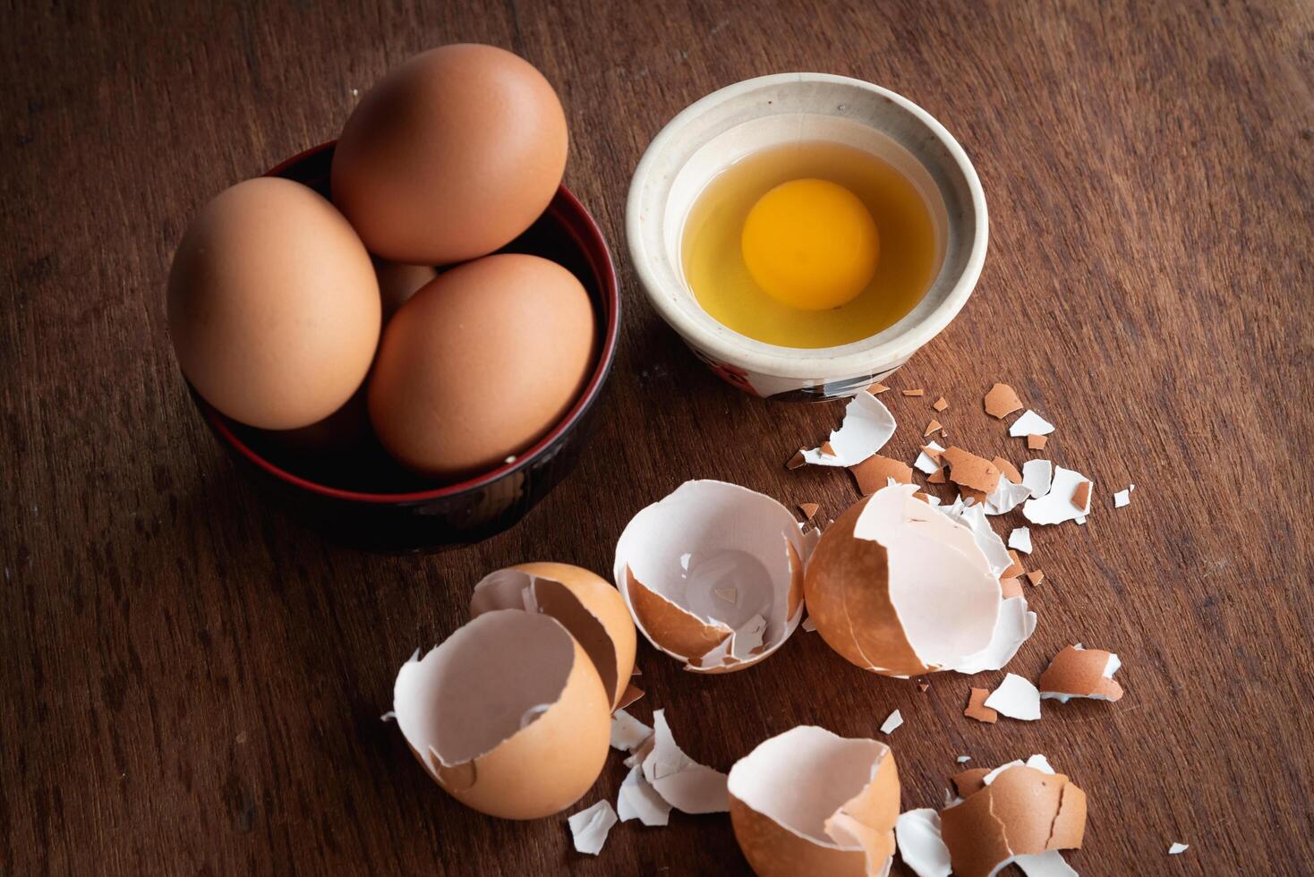 Broken egg shells and eggs on tray at wooden background photo