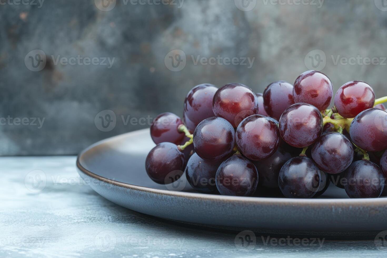 Fresh red grapes in a dark plate on a textured surface, showcasing natural colors and freshness photo