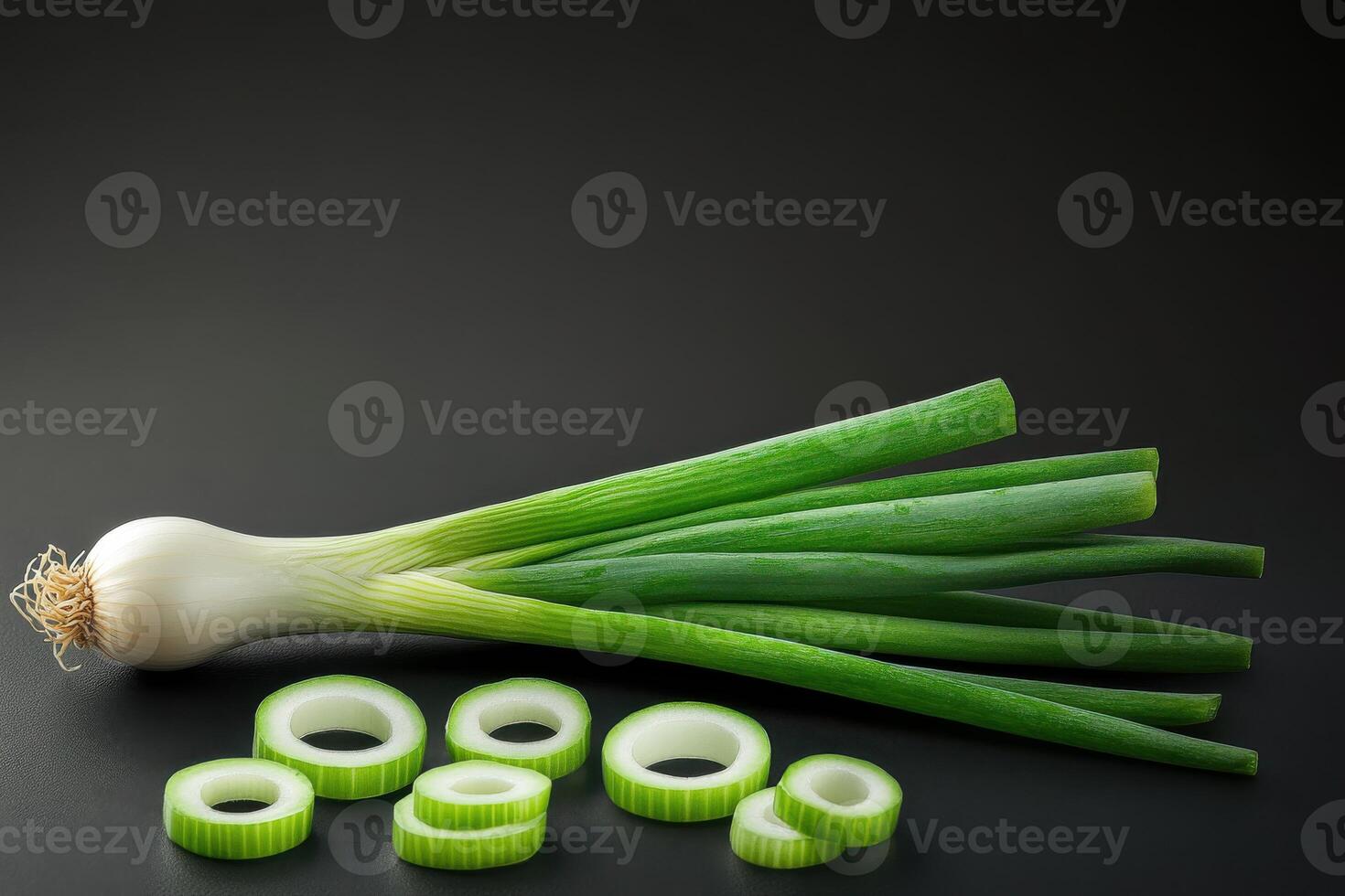 Fresh green onions displayed on a dark background with sliced rings beside whole stalks ready for culinary use photo