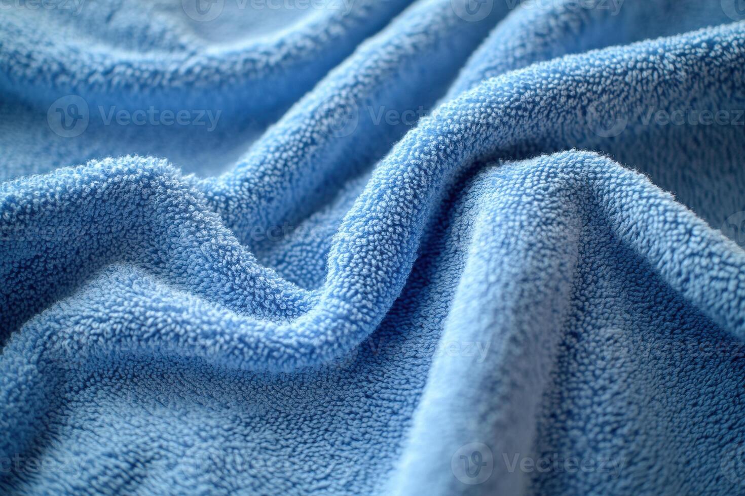 Soft blue fabric drapes in gentle folds on a textured surface illuminated by natural light photo