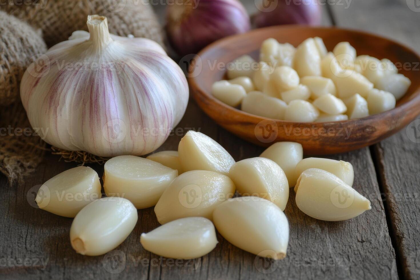 Fresh garlic bulbs and peeled cloves arranged on a rustic wooden table with a bowl of chopped garlic on the side photo