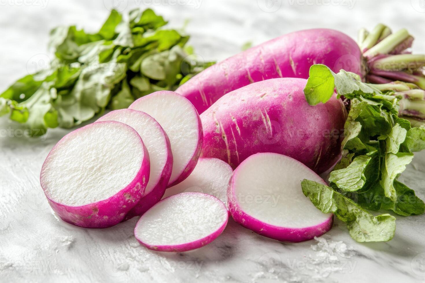 Freshly sliced pink radishes accompanied by vibrant green leaves on a rustic surface in natural light photo