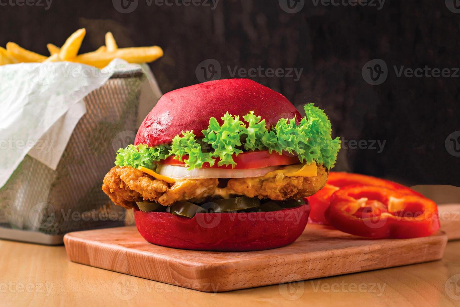 Crispy Chicken Burger with Lettuce, Jalapeno, Tomato, Cheese isolated on wooden board with french fries basket side view of fastfood photo