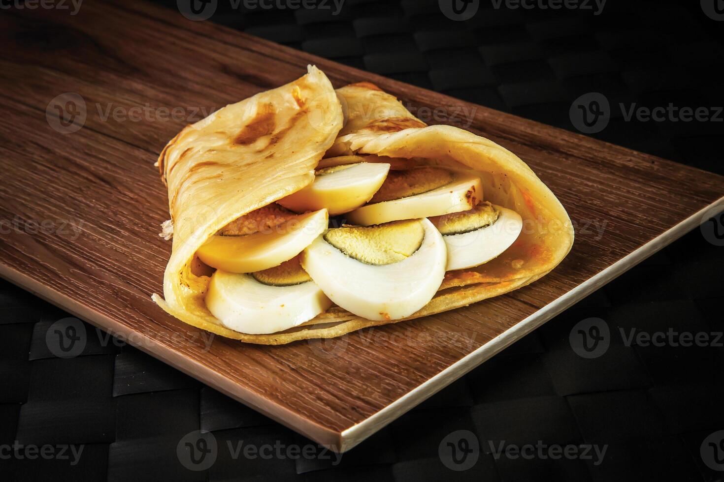 Boiled Egg Paratha Roll shawarma wrap isolated on wooden board closeup side view of oman fastfood photo
