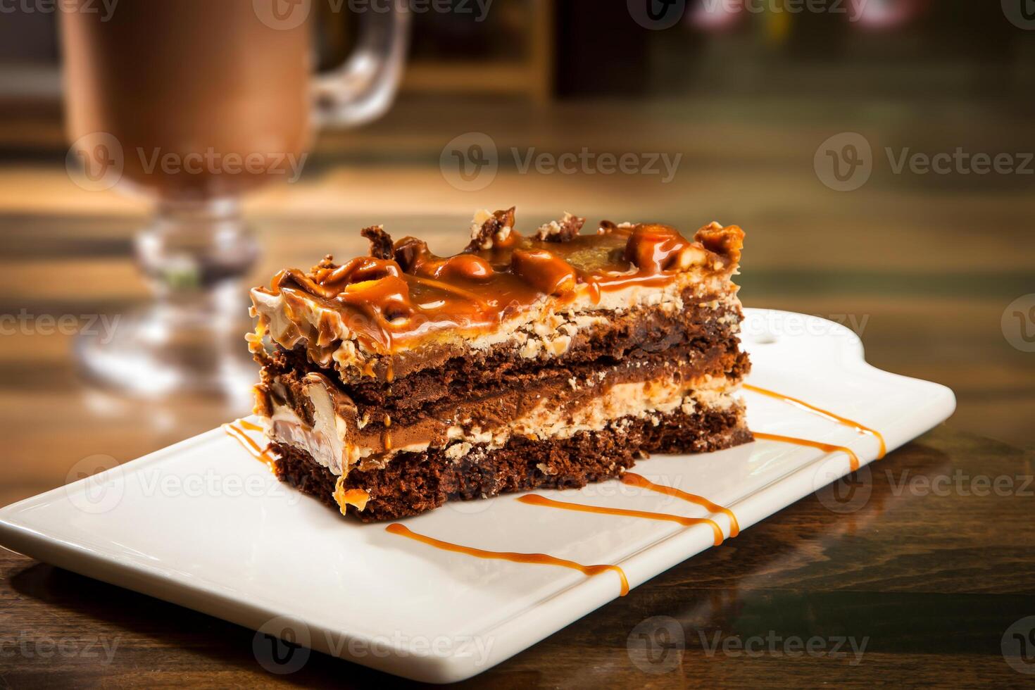 Decadent Chocolate Caramel Layer Cake with Drizzle Chocolate Sauce and Hot Chocolate Coffee mug served in tray dish isolated on table side view of cafe baked dessert food photo