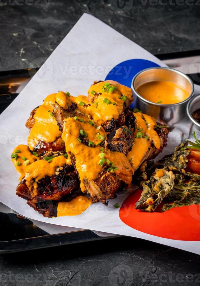 Grilled Peri Peri Chicken with Creamy Sauce and Crispy Garnish served in tray isolated on grey background closeup side view of A la carte Food platter photo