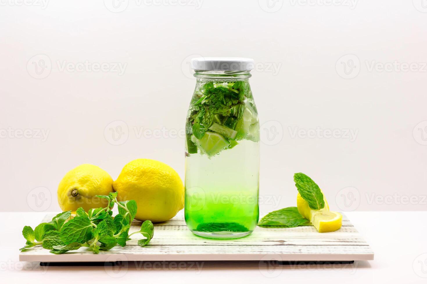 Green Apple Mojito Soda with Lime and Mint served in bottle isolated on wooden board side view of cold beverage on white background photo